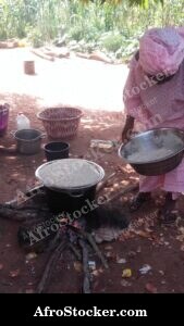 Woman Tending Cooking Pots in African Kitchen